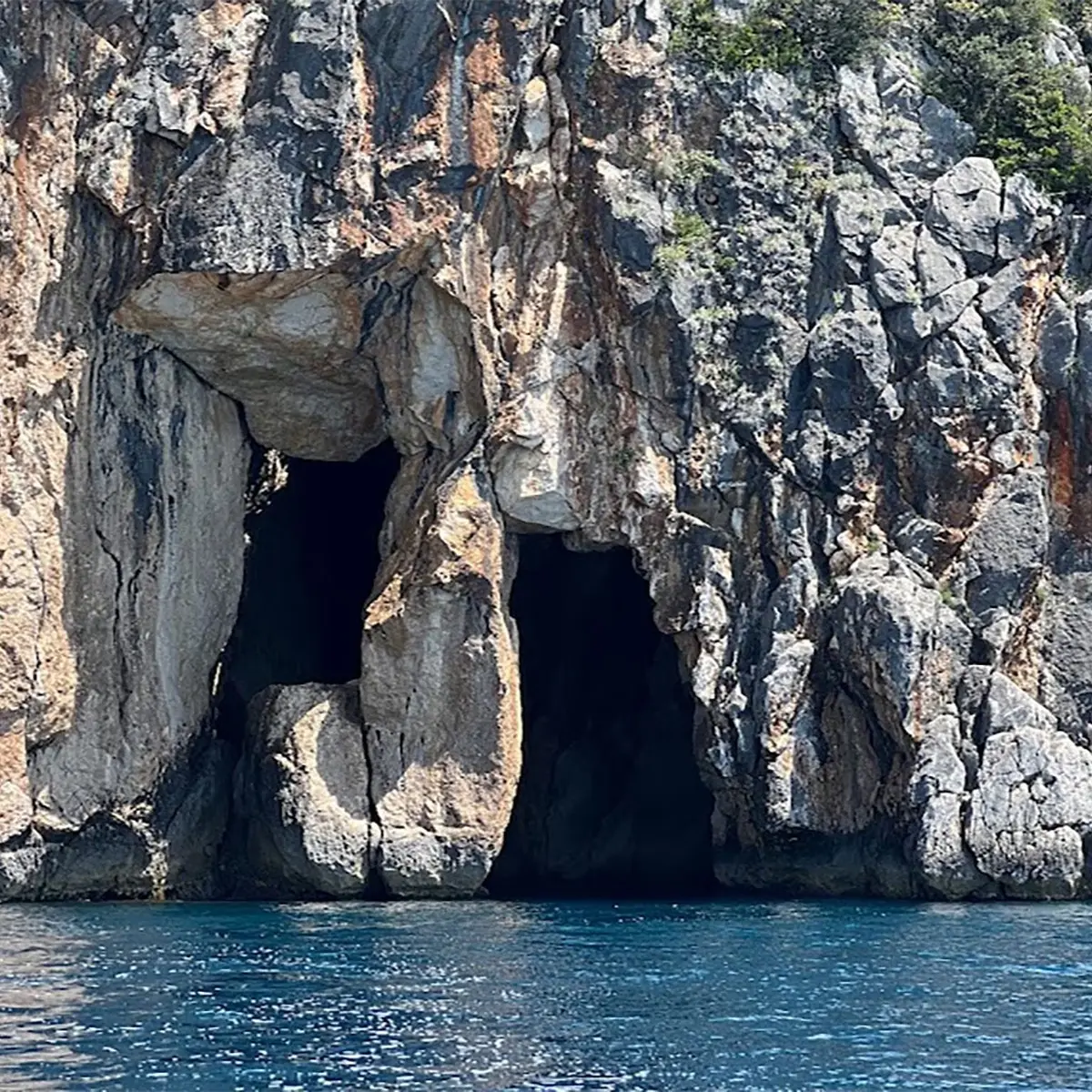 Pirates Cave boat tour with crystal-clear waters and rocky coastline