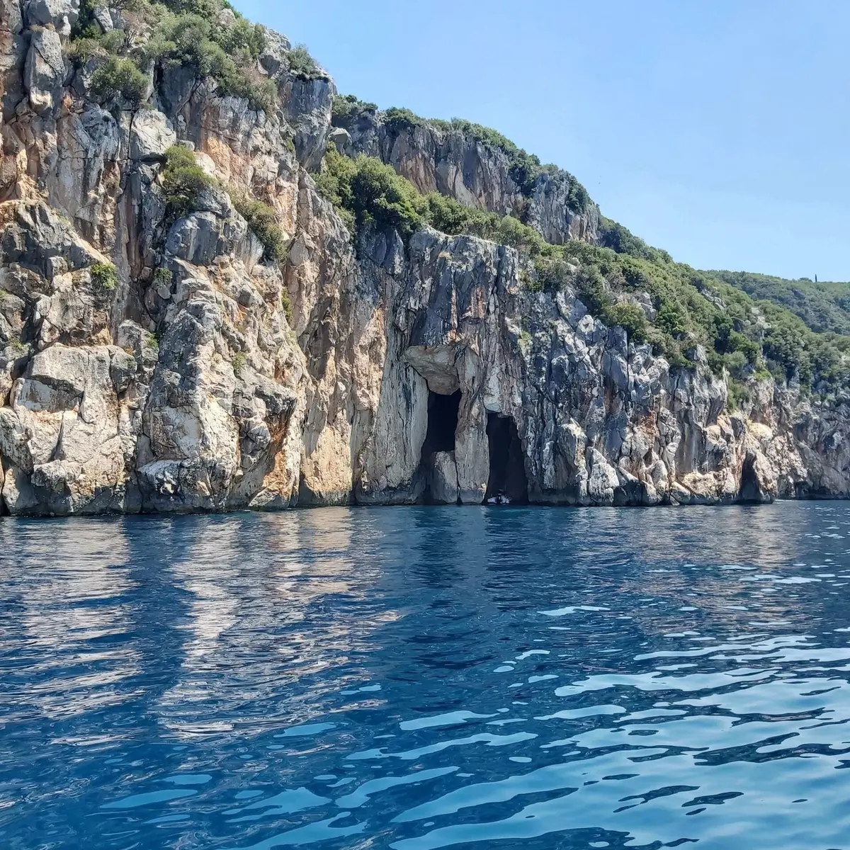 Pirates Cave boat tour with crystal-clear waters and rocky coastline
